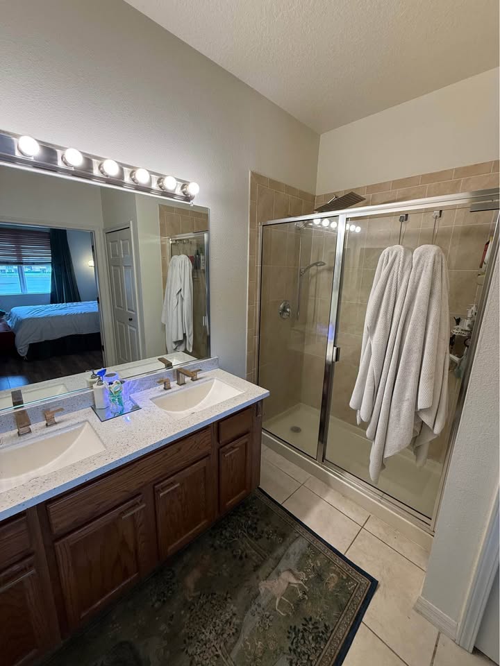Primary bathroom with dual sinks and glass shower